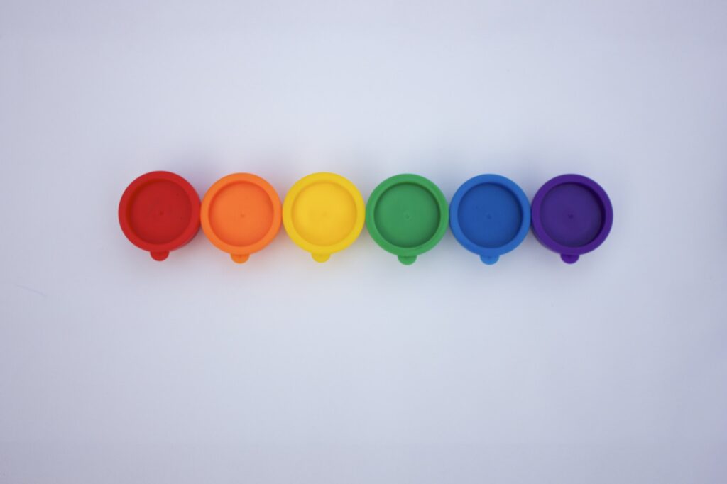 Rainbow row of bright and colorful paints against white background